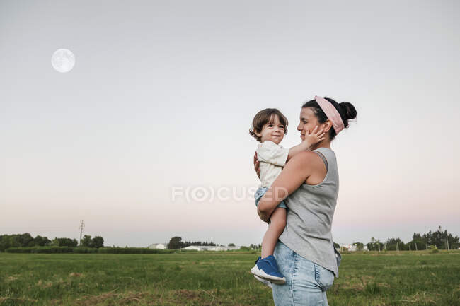 Mother looking while carrying son during sunset — Stock Photo
