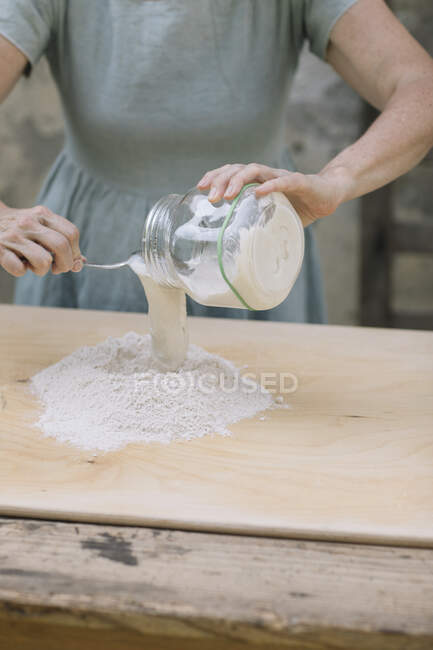 Mature woman pouring milk on flour at back yard — Stock Photo