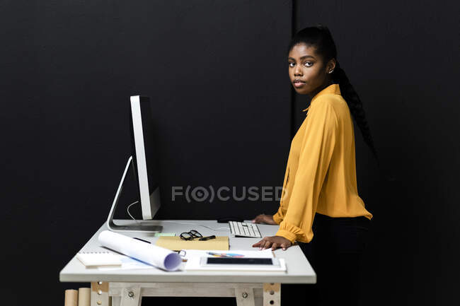 Femme professionnelle travaillant en studio par mur noir — Photo de stock
