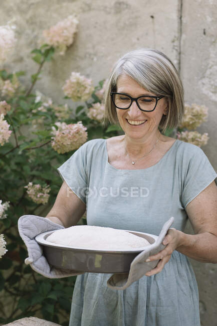 Возбужденная женщина несет сковороду для выпечки на заднем дворе — стоковое фото