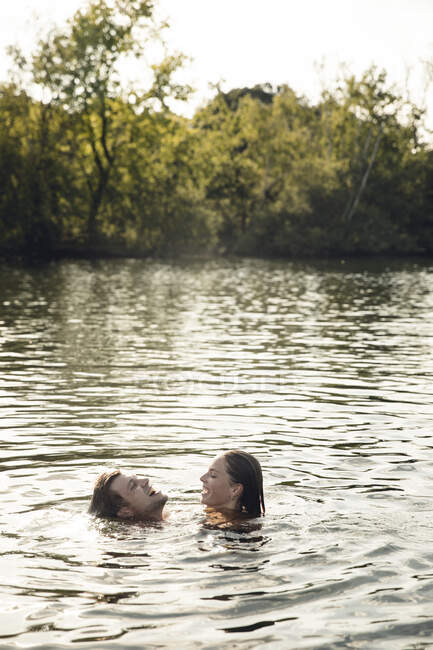 Pareja cariñosa nadando juntos en un lago - foto de stock