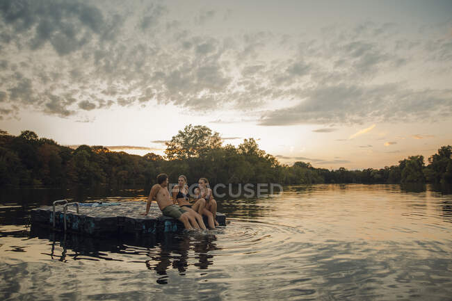 Friends having fun at the lake, sitting on bathing platform — Stock Photo