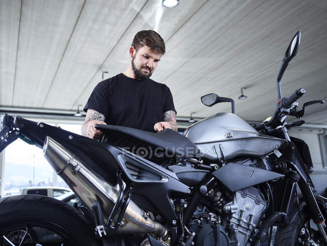 Young male repairman installing motorcycle part at garage — Stock Photo