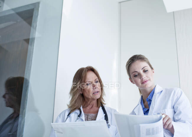 Médicos mirando documentos mientras discuten en el hospital - foto de stock