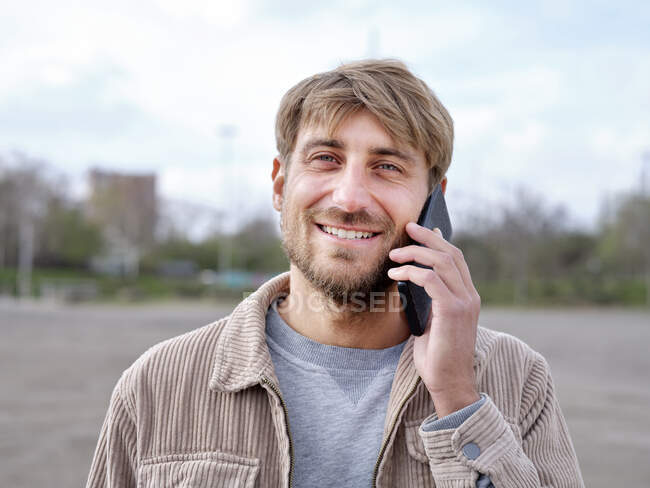 Sonriente hombre guapo hablando por teléfono móvil - foto de stock
