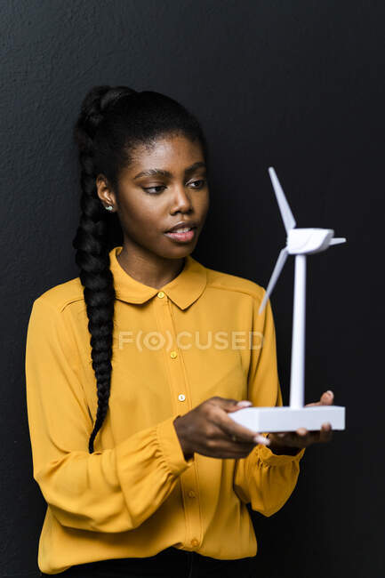 Femme d'affaires tenant le modèle d'éolienne devant un mur noir au studio — Photo de stock
