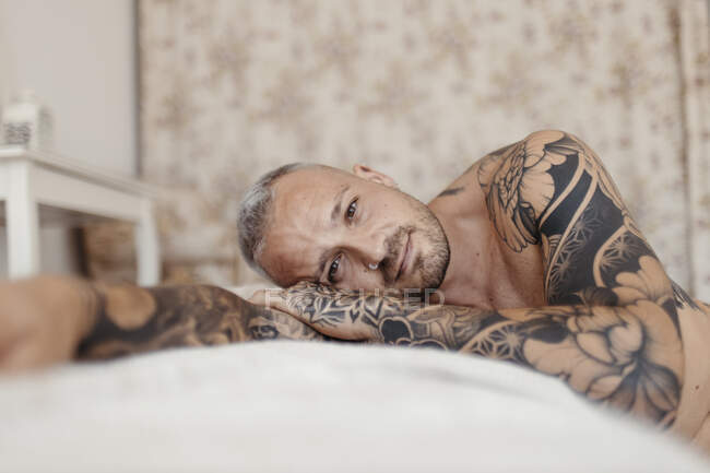 Hombre guapo con anillo en la nariz acostado en la cama en casa — Stock Photo
