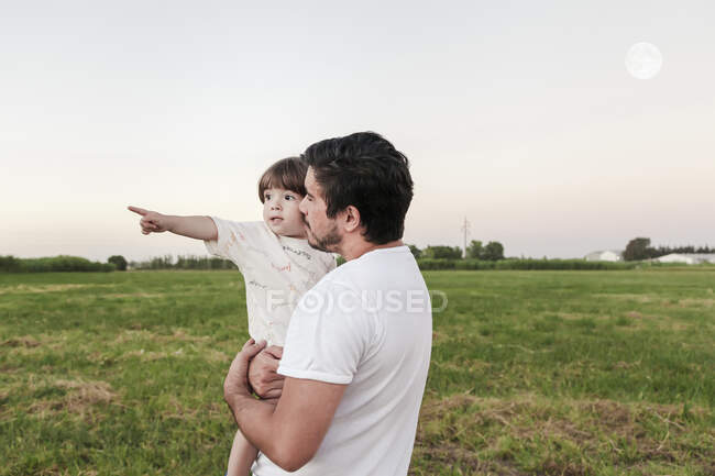 Uomo che trasporta il bambino mentre in piedi sull'erba — Foto stock