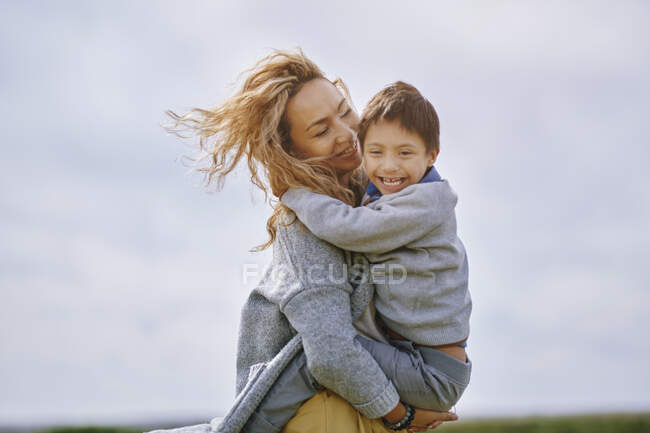 Madre llevando feliz hijo con síndrome de Down - foto de stock