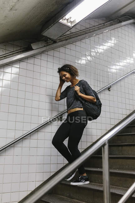 Giovane donna con la testa in mano scendendo sui gradini della metropolitana — Foto stock