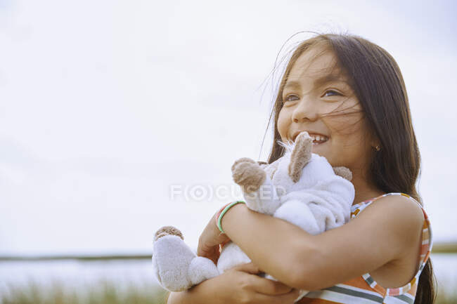 Menina bonito olhando embora enquanto segurando pelúcia urso de pelúcia — Fotografia de Stock