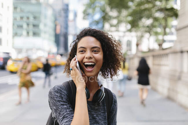 Woman laughing while talking on smart phone in city — Stock Photo