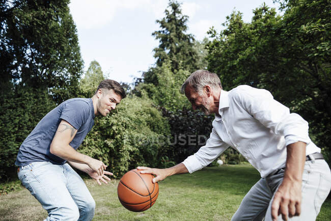 Vater spielt bei sonnigem Tag mit Sohn Basketball im Hinterhof — Stockfoto