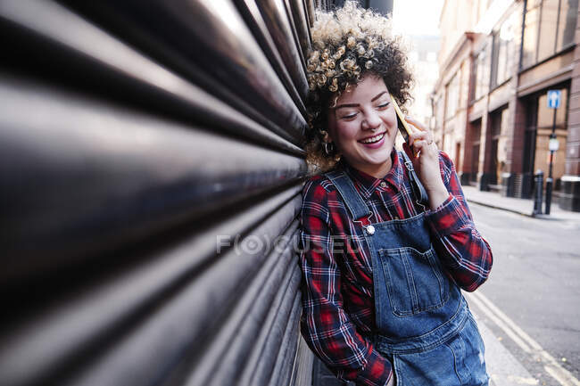 Felice hipster donna che parla attraverso lo smart phone mentre si appoggia sull'otturatore — Foto stock