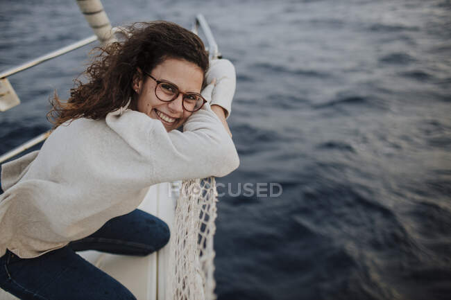 Щаслива жінка в окулярах спирається на сітку на човні під час відпустки — стокове фото