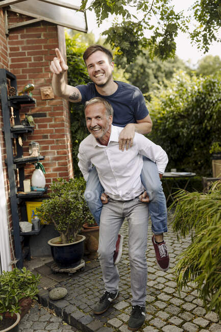 Ältere Vater geben huckepack Fahrt zu Sohn zeigt in Hinterhof — Stockfoto