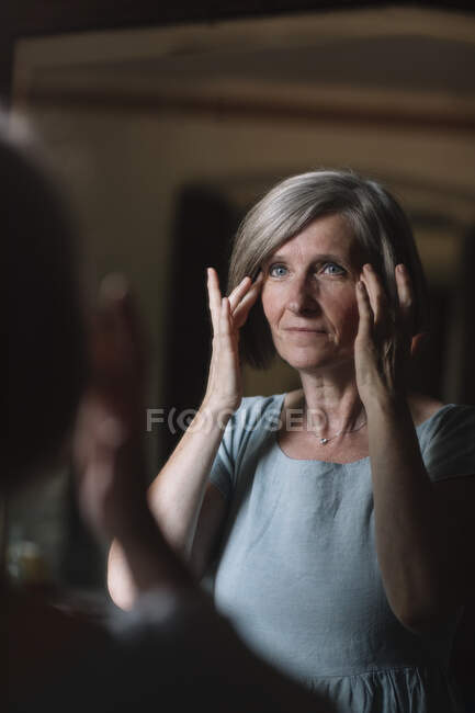 Schöne reife Frau schaut in den Spiegel er Jahre Menschen Stock Photo