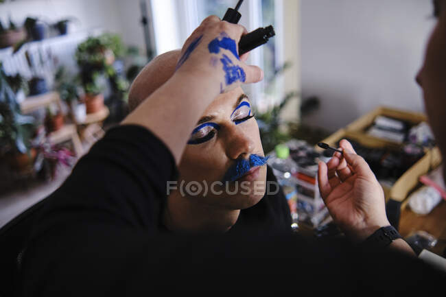 Truccatore femminile che applica il trucco sul modello maschile in studio — Foto stock