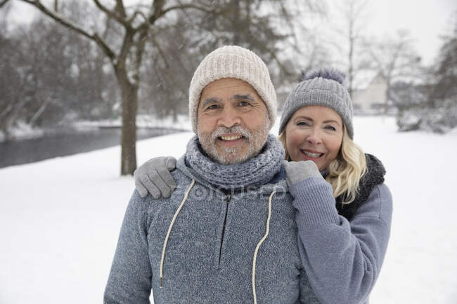 Улыбающаяся женщина в теплой одежде, стоящая с мужчиной в парке — стоковое фото