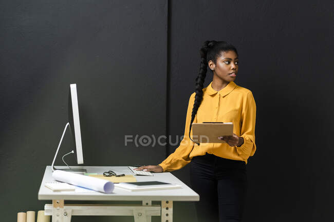 Femme d'affaires cheveux tressés détournant les yeux tout en travaillant en studio — Photo de stock