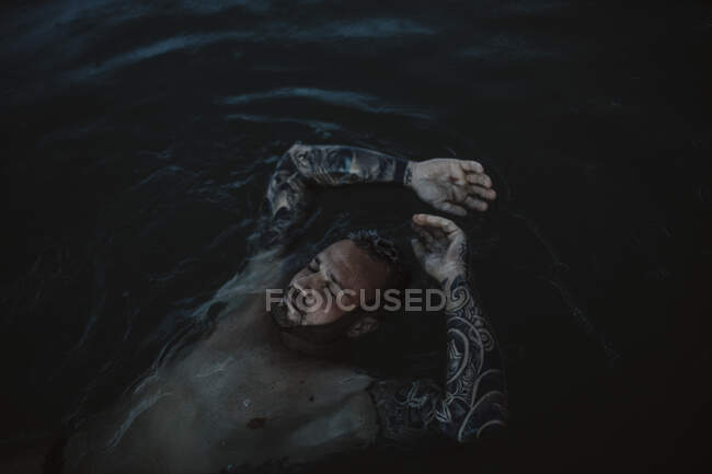 Uomo con gli occhi chiusi galleggiante sull'acqua in mare — Foto stock