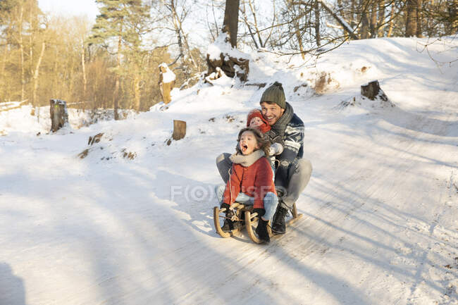 Luge ludique avec père et frère sur la neige pendant l'hiver — Photo de stock