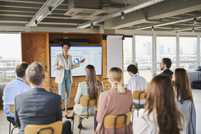 Mid adult businesswoman explaining business strategy to colleagues in training class — Stock Photo