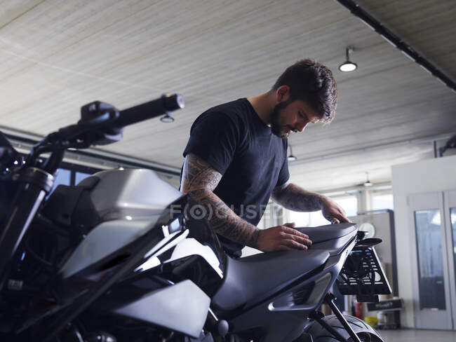 Reparador instalando asiento de motocicleta en el taller - foto de stock