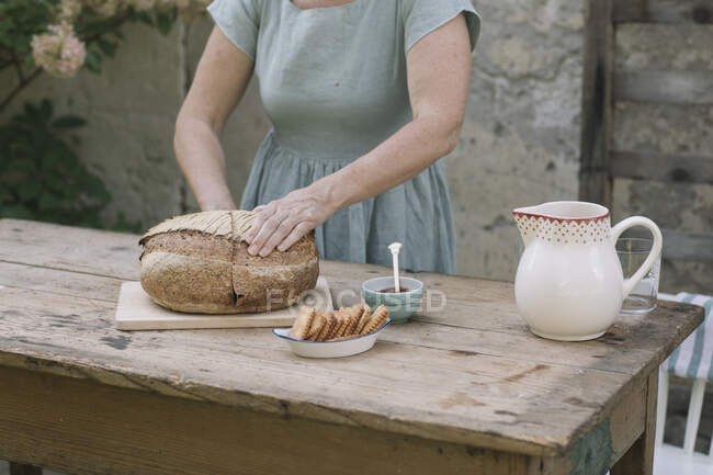 Зріла жінка перевіряє хліб на задньому дворі — стокове фото