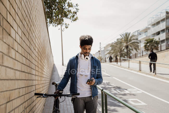Mann benutzt Handy, während er mit Fahrrad auf Fußweg steht — Stockfoto