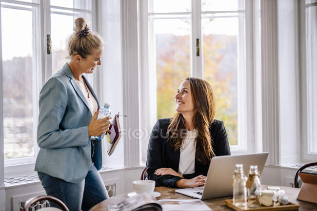 Smiling businesswomen discussing with female colleague in office — Stock Photo
