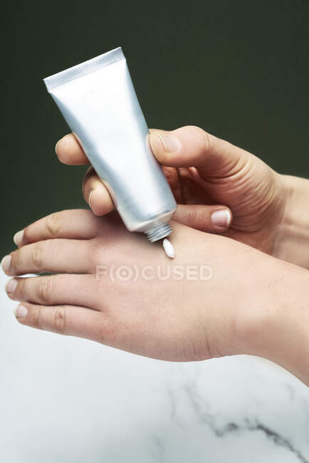 Woman taking hand cream over green background — Stock Photo