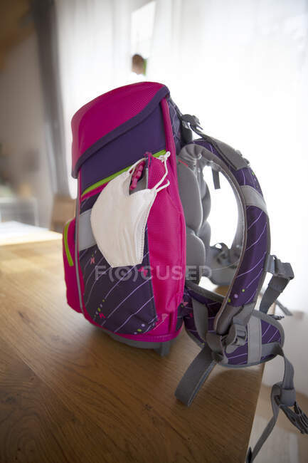 Рюкзак с защитной маской за столом — стоковое фото