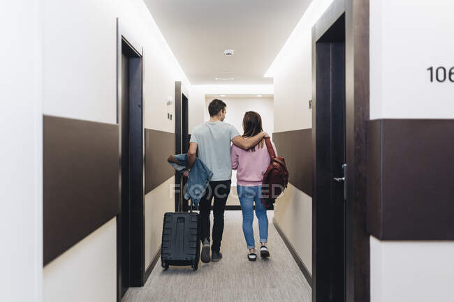 Couple walking with luggage at hotel corridor — Stock Photo