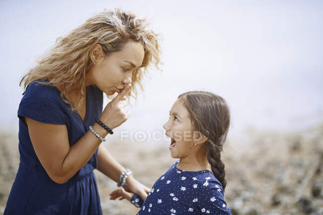 Madre gesticolando con il dito sulle labbra alla figlia — Foto stock