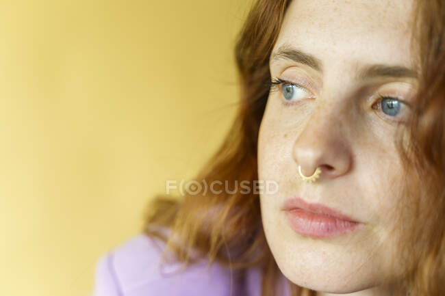 Beautiful woman with gray eyes looking away in front of yellow background — Stock Photo
