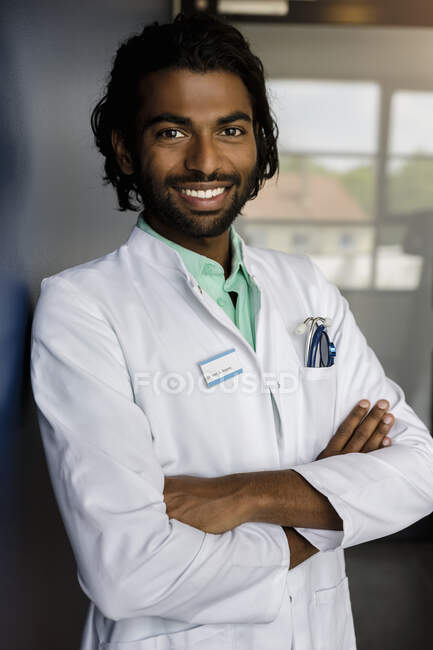 Fiducioso medico maschio in piedi con le braccia incrociate in ospedale — Foto stock