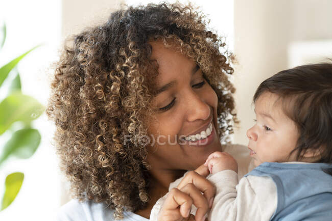 Счастливая мать улыбается своему миленькому ребенку дома — стоковое фото