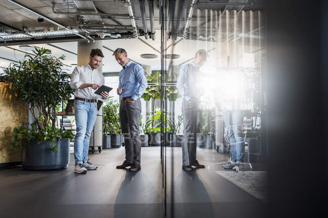 Business people working on digital tablet while standing in office — Stock Photo