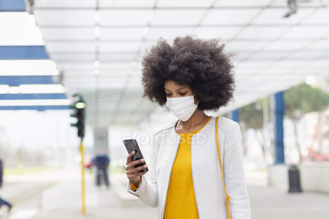 Afro-Geschäftsfrau benutzt während Pandemie Smartphone am Bahnhof — Stockfoto