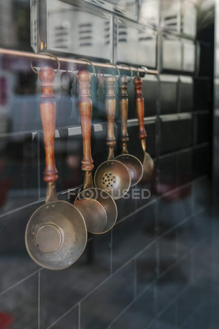 Varios utensilios de cocina colgados en una pared vista a través de vidrio en el restaurante - foto de stock