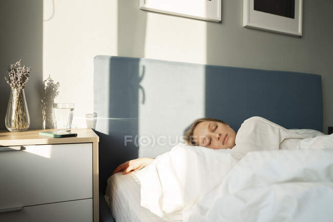 Jeune femme dormant au lit à table à la maison — Photo de stock