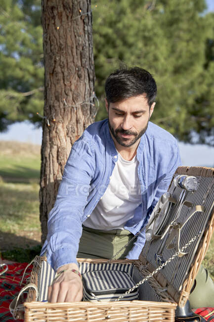 Mann sucht im Urlaub in Picknickkorb im Park — Stockfoto