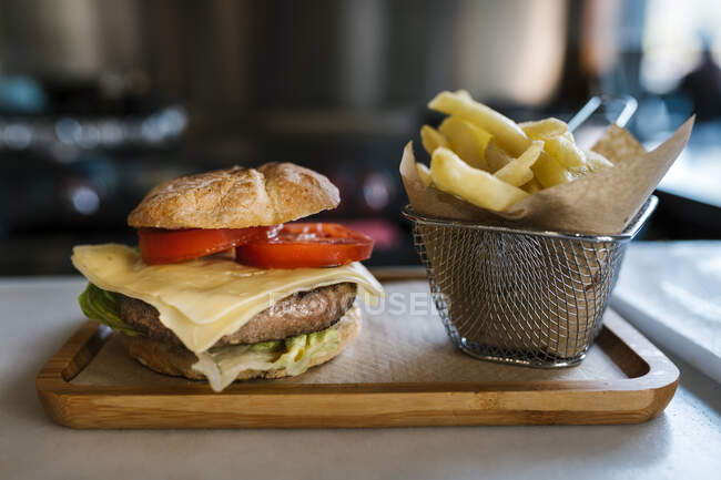Burger and french fries on wooden tray at restaurant — Stock Photo