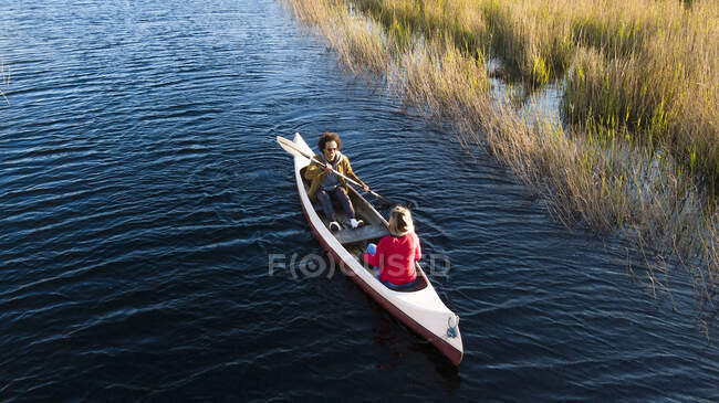 Homem com remo remando enquanto sentado com mulher em canoa no rio — Fotografia de Stock