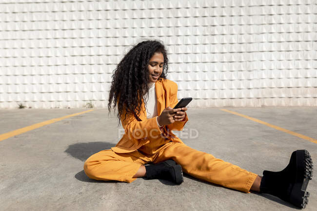 Curly mulher de cabelos ruivos usando telefone enquanto sentado no caminho — Fotografia de Stock