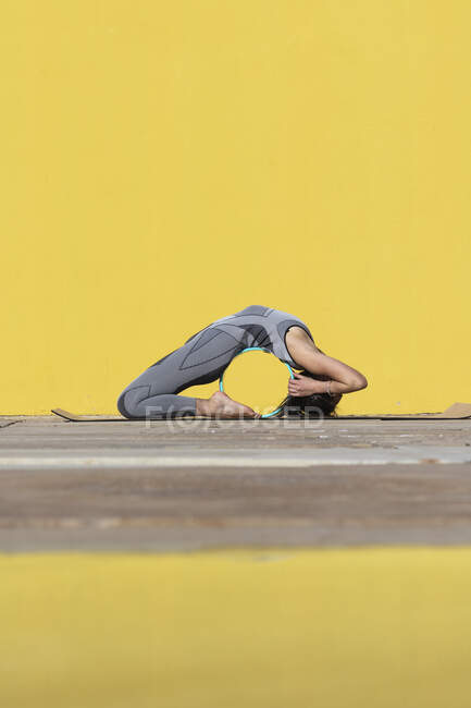 Woman doing yoga wheel exercise while bending over backwards by wall — Stock Photo