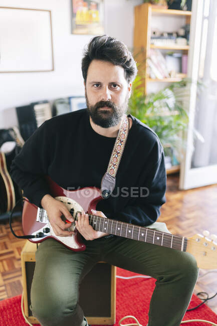 Músico masculino sentado con guitarra en el estudio - foto de stock