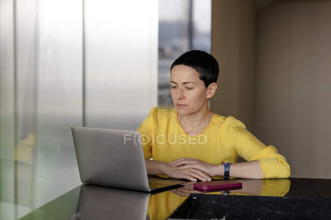 Grave imprenditrice in cerca di laptop in ufficio — Foto stock