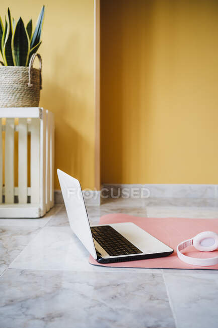Laptop and headphones on exercise mat at home — Stock Photo